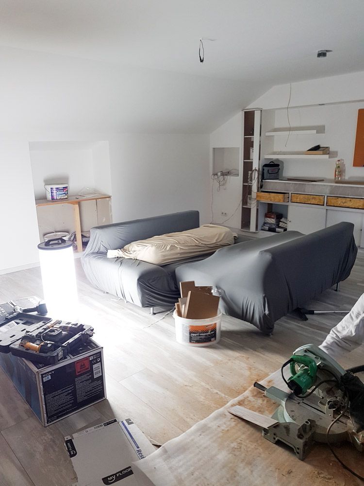 Renovierungsraum mit abgedeckten Sofas Werkzeugen und Kappsaege auf Holzboden
