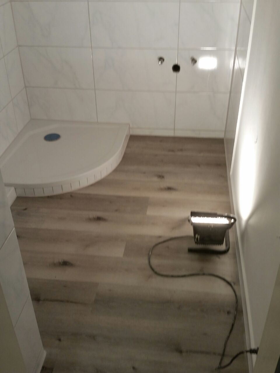 Renoviertes Badezimmer mit weisser Duschwanne und hellem Holzboden