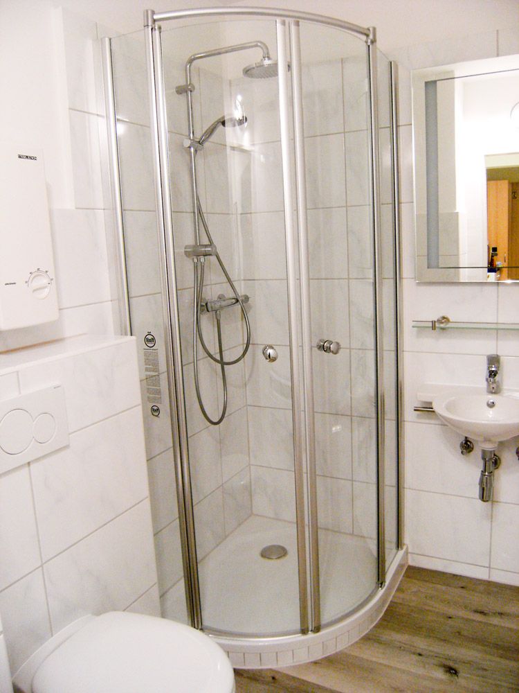 Modernes weisses Badezimmer mit runder Duschkabine Waschbecken und Spiegel