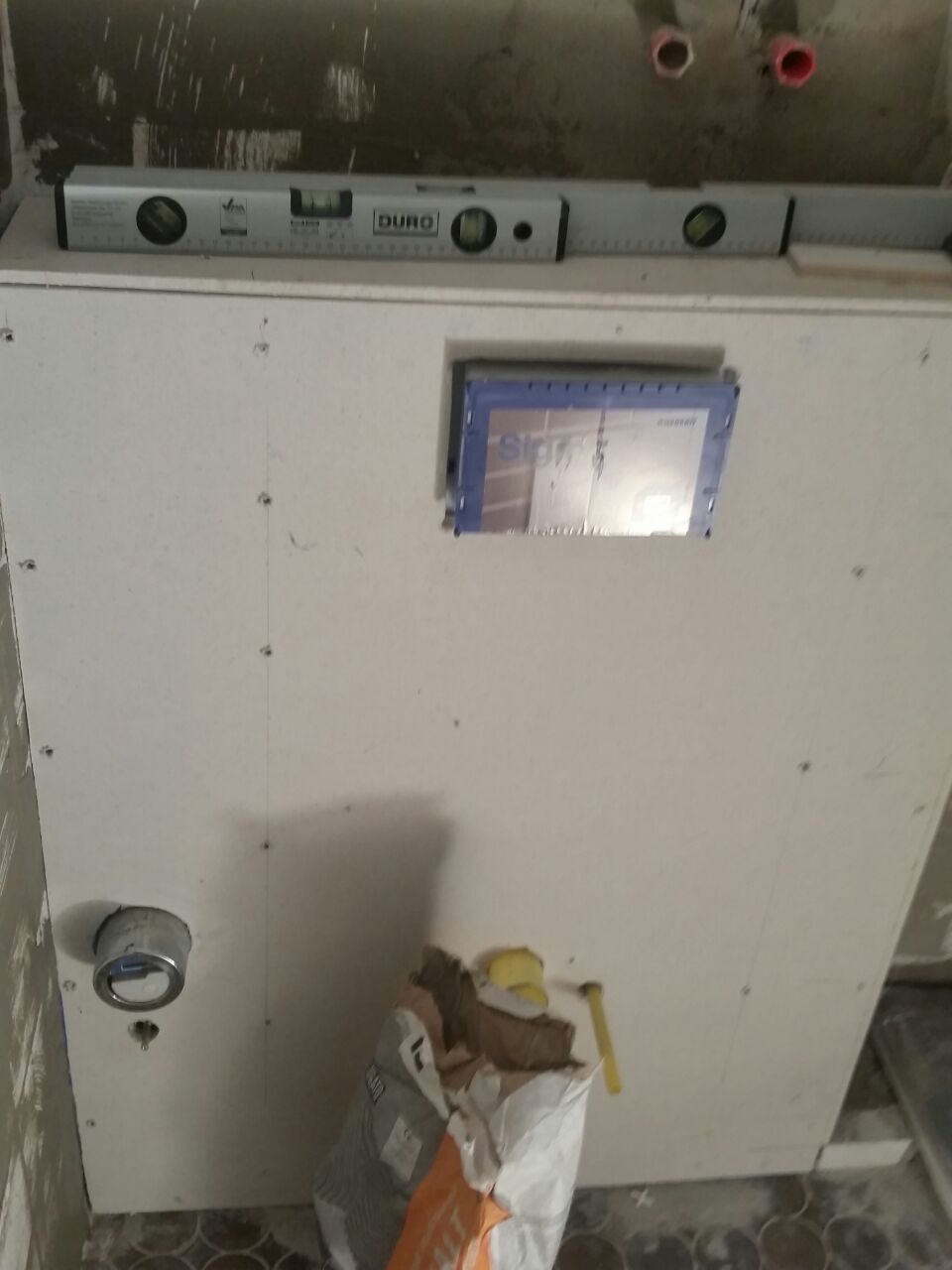 Wasserwaage auf Trockenbauwand mit Aussparung fuer WC Spuelkasten auf Baustelle