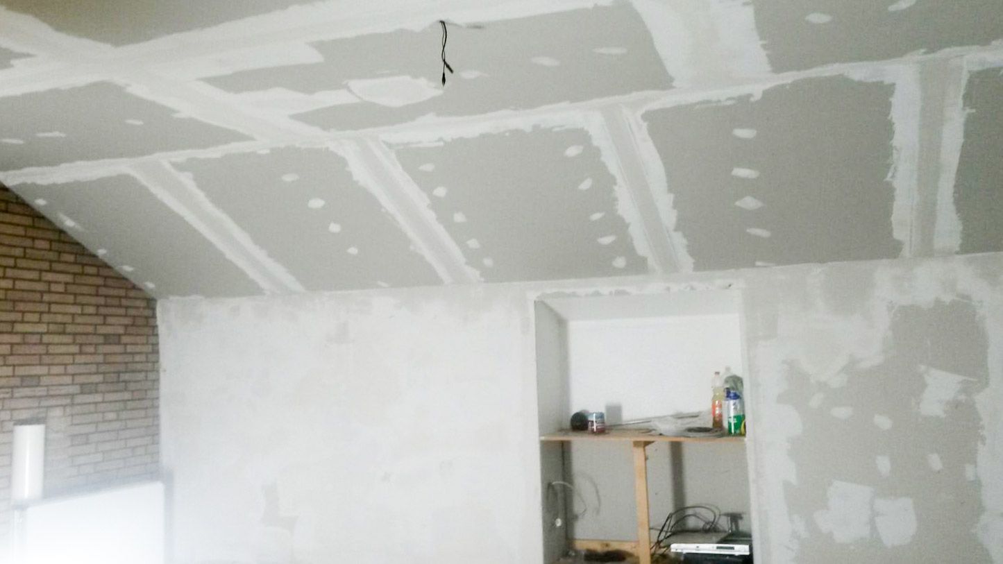 Baustelle mit verspachtelter Rigipsdecke Ziegelwand und Getraenkeflaschen in Nische